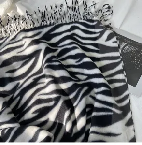 Close-up detail of stylish black and white zebra pattern winter tassel scarf and warm shawl.