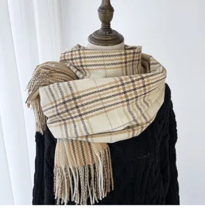 Primo piano di una sciarpa a quadri beige e marrone accogliente con frange per donna inverno.