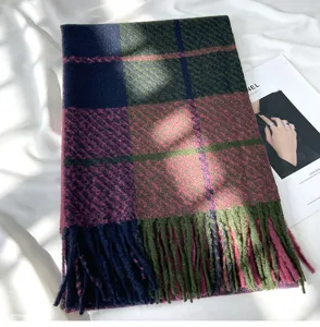 Detailed shot of a cozy plaid tassel scarf in navy pink and olive green for winter.