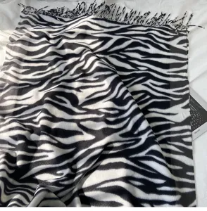 Close-up detail of black and white zebra print cashmere feel scarf with tassel edge.