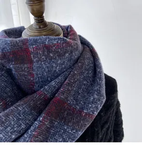 Detail shot of a cozy plaid winter scarf in blue and red tones, soft and warm texture.
