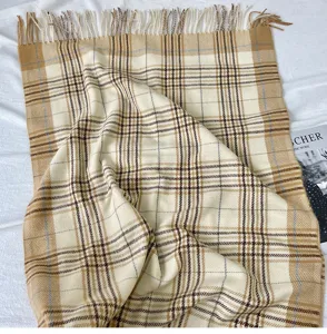 Vista dettagliata di una morbida sciarpa a quadri beige e marrone con eleganti frange.