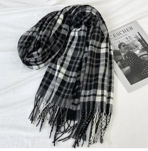 Detail shot of a black, white and grey plaid winter fringed scarf on white background.