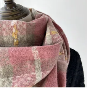 Plaid winter scarf detail showing soft imitation cashmere fabric texture and warm pink gray tones.