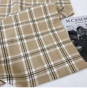 Close-up detail of cozy plaid scarf featuring classic beige and white checkered pattern.