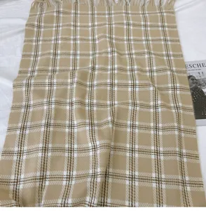 Detailed view of the soft beige plaid scarf fabric texture and elegant tassel design.