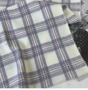 Close-up detail of soft plaid winter scarf fabric, showing delicate texture and purple pattern.
