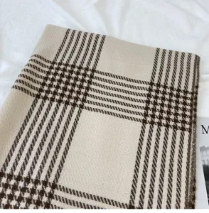 Nahaufnahme Detail von gemütlichem karierten Schal in Braun und Beige mit feiner Webstruktur.