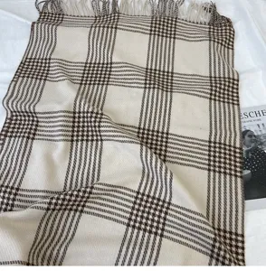 Nahaufnahme eines klassischen beige und braunen Karosschals mit feinen Fransen im Detail.