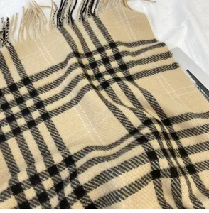 Classic plaid scarf texture detail showing soft cashmere-feel fabric and fringe ends.
