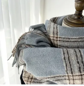 Detailed shot of a blue-grey plaid scarf featuring soft textured fabric and elegant fringe.
