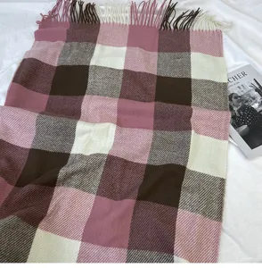 Detailed view of women's cozy checkered scarf with chic pink and brown blocks and stylish fringe.