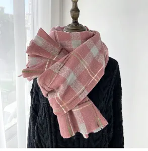 Close-up detail of the cozy pink plaid winter scarf, soft texture and fringed hem design.