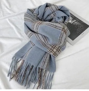 Close-up of cozy blue plaid winter scarf with chic fringe details. Soft knitted texture.