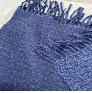 Close-up detail of soft blue knitted winter scarf with elegant fringes cozy warm fashion accessory