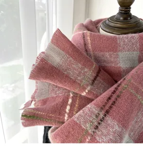 Detailed close-up of a cozy pink and grey plaid winter scarf, showcasing soft knit texture.