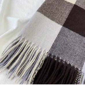 Detailed view of winter plaid scarf with fringe, soft texture and warm brown grey tones.