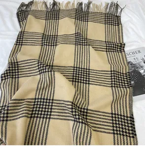 Detailansicht eines klassischen karierten Winterschals in Beige und Schwarz mit Fransen.
