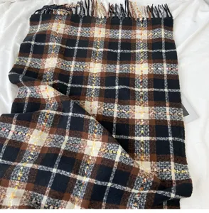 Close up detail of winter thick plaid scarf, black brown white pattern with warm fringe.