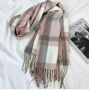 Detailed shot of soft pink and grey plaid winter scarf featuring cozy fringe tassels.