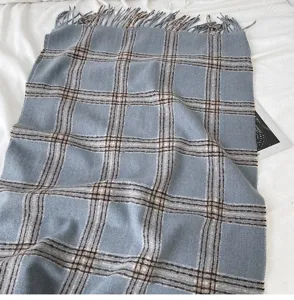 Detailed view of cozy blue plaid winter scarf with warm tassels texture and classic pattern.