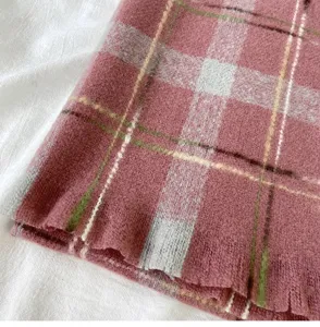 Close-up detail of cozy pink plaid winter scarf texture with soft woolen fabric pattern.