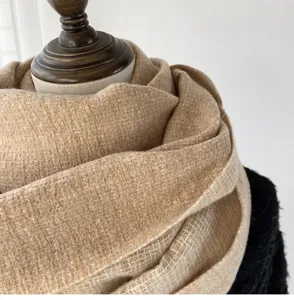 Close-up detail of cozy winter imitation cashmere scarf in camel, soft warm textured fabric.