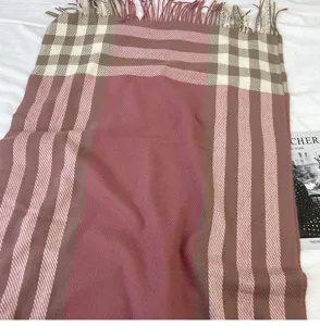 Close-up detail of the pink and brown plaid winter tassel scarf, soft cashmere-feel fabric.
