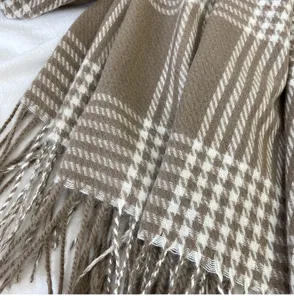Nahaufnahme eines braun-weißen Hahnentritt-Winterschals mit gemütlichem Fransen-Design.