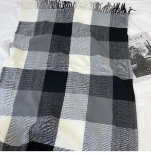 Black and white plaid scarf detail showing classic pattern and cozy tassel fringe trim.