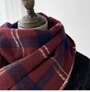 Closeup detail of cozy winter plaid scarf in burgundy and navy blue colors texture.