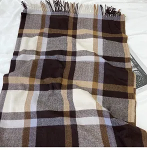 Detailed view of winter brown plaid tassel scarf, soft cashmere-feel fabric texture.