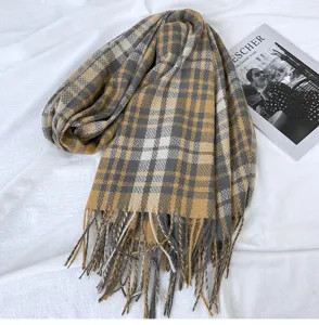 Detailed view of a soft yellow and grey plaid tassel scarf, showcasing texture and fabric.