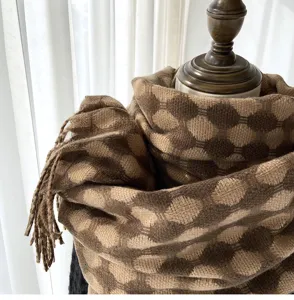 Cozy brown round plaid winter scarf with cute tassels, soft imitation cashmere fabric close-up view.