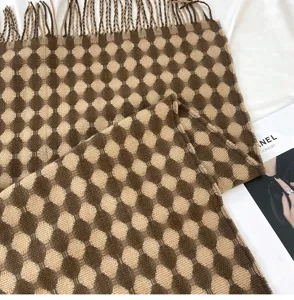 Close-up detail of soft brown grid pattern cashmere-feel winter scarf with tassels.
