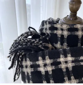 Close-up detail of black and white plaid cashmere-feel winter warm scarf with soft fringe trim.