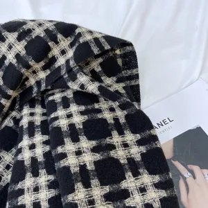 Detailed view of black and white plaid winter scarf, soft knitted texture close-up shot.