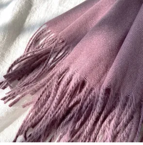 Detailaufnahme eines weichen, violetten Winterschals in Kaschmir-Optik mit Fransen.
