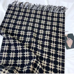 Detailed view of winter black and white plaid scarf with fringe, soft cozy texture close-up.