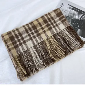 Close-up detail of the brown plaid winter scarf, showing soft texture and tassel hem design.