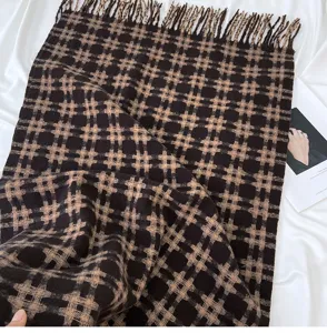 Detailed shot of the retro black and brown plaid winter scarf with cozy fringe texture.