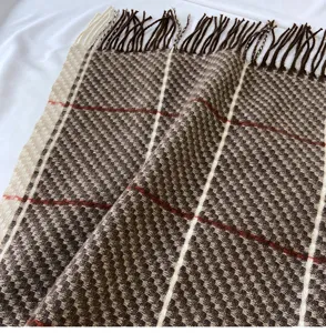 Detailed close-up of brown plaid imitation cashmere scarf with fringe, soft winter warm accessory.