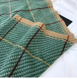 Close-up detail of a soft imitation cashmere plaid scarf in green and khaki. Autumn winter warm wrap.