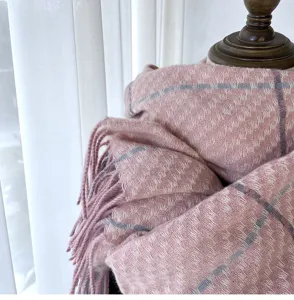 Soft pink plaid winter scarf detail featuring cozy woven texture and classic fringe edges.