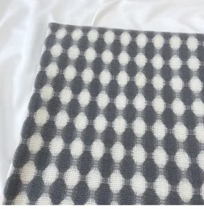 Detailed view of grey and white dotted knitted scarf fabric, soft texture, cozy winter style.
