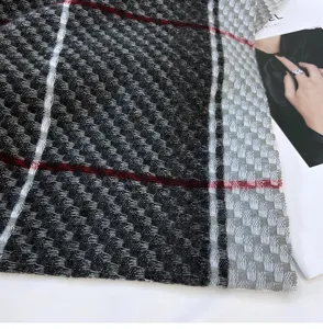 Close-up detail of soft knit plaid scarf texture, showcasing warm black and grey woolen fabric.