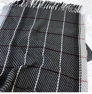 Close-up detail of a classic black and white plaid scarf featuring stylish fringe trim.