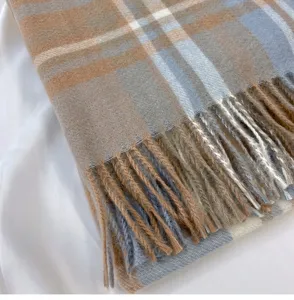Close-up detail shot of a classic plaid fringed cashmere-feel scarf, soft and textured.