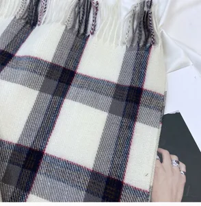 Gros plan détaillé sur l'écharpe d'hiver à carreaux, texture douce et belles franges.