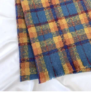 Close up view of blue and yellow plaid winter scarf, soft knit texture with fringe detail.